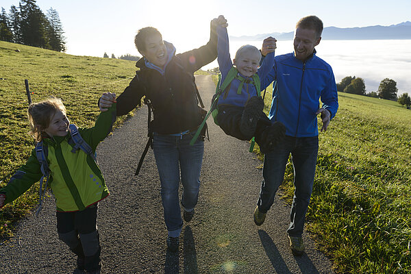 Junge Familie wandert in den Morgenstunden auf den Auerberg bei Bernbeuren.