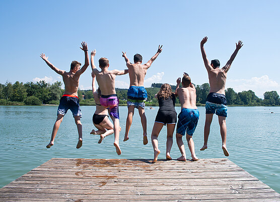 Jugendliche genießen den Sprung ins kühle Nass am Dietlhofer See in Weilheim.